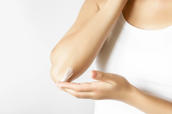 lady applying cream on her elbows for lighting black elbows.