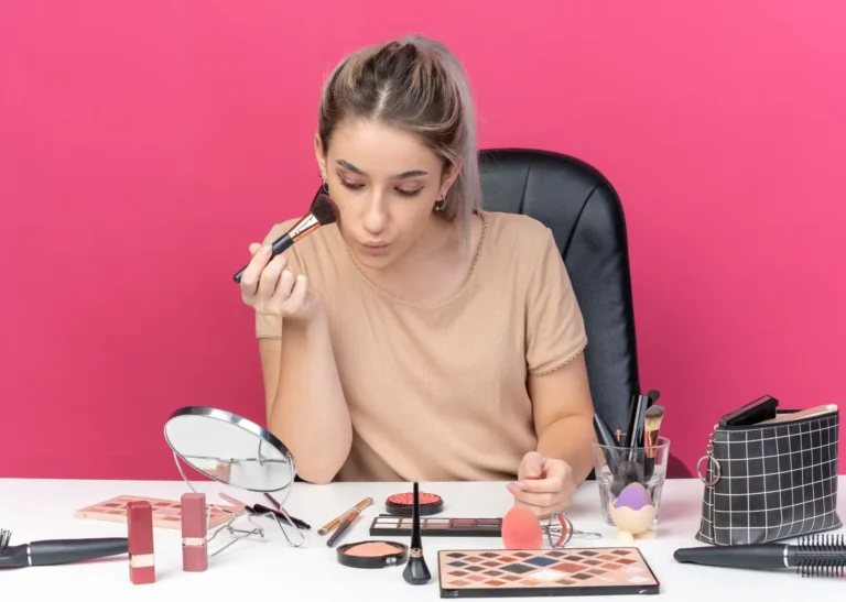Looking in front of the mirror and doing her everyday makeup routine, a young, beautiful lady.