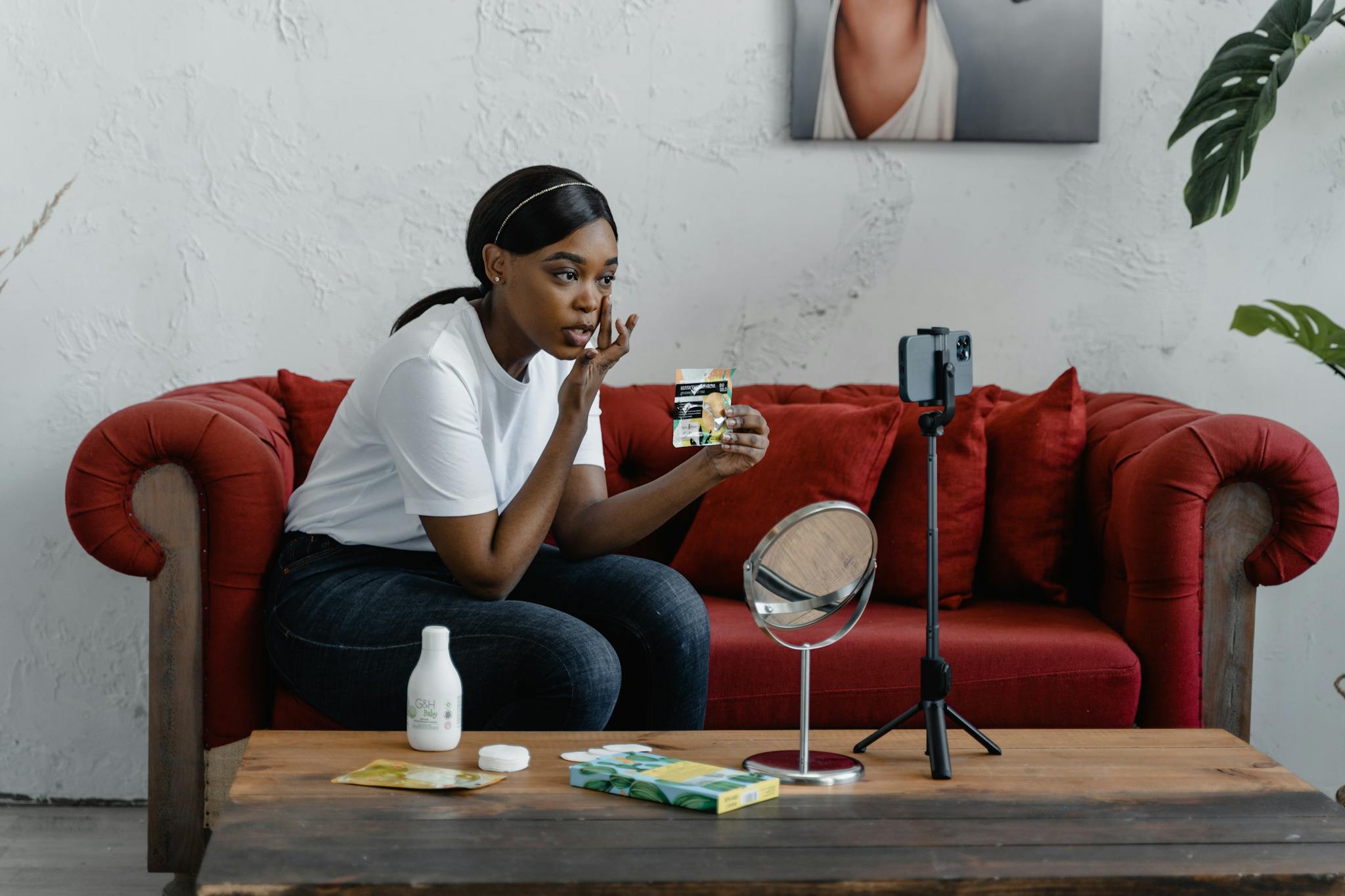 A woman records a makeup tutorial in a cozy indoor setting with cosmetics and a smartphone stand. and it's appearing in the home page section.